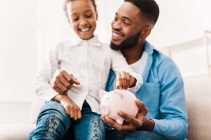 Girl and father putting coin into piggy bank